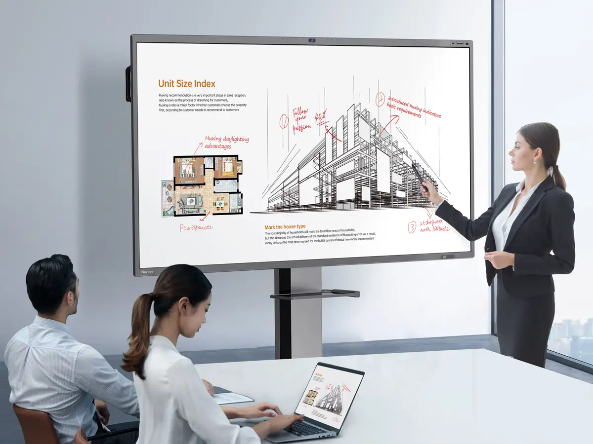 A woman annotating a presentation on a Horion panel in an office, colleagues at the table with laptops