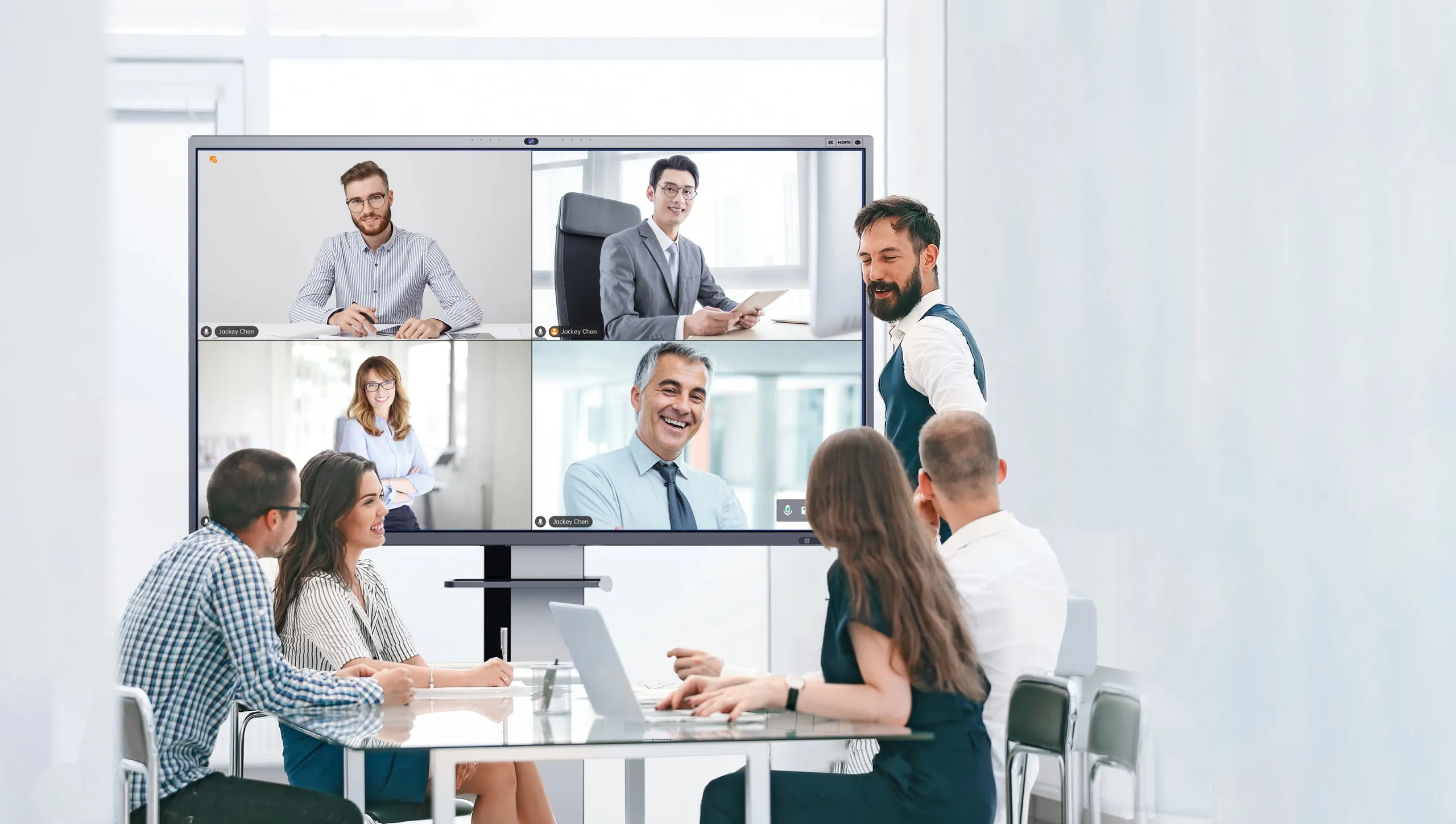 A team of four in a meeting room talking to remote colleagues via a Horion panel